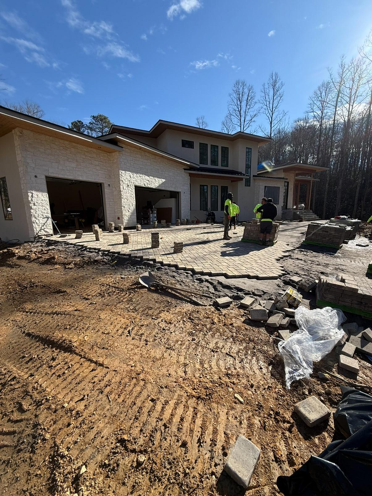 Modern white stone estate with paver driveway being laid by the crew